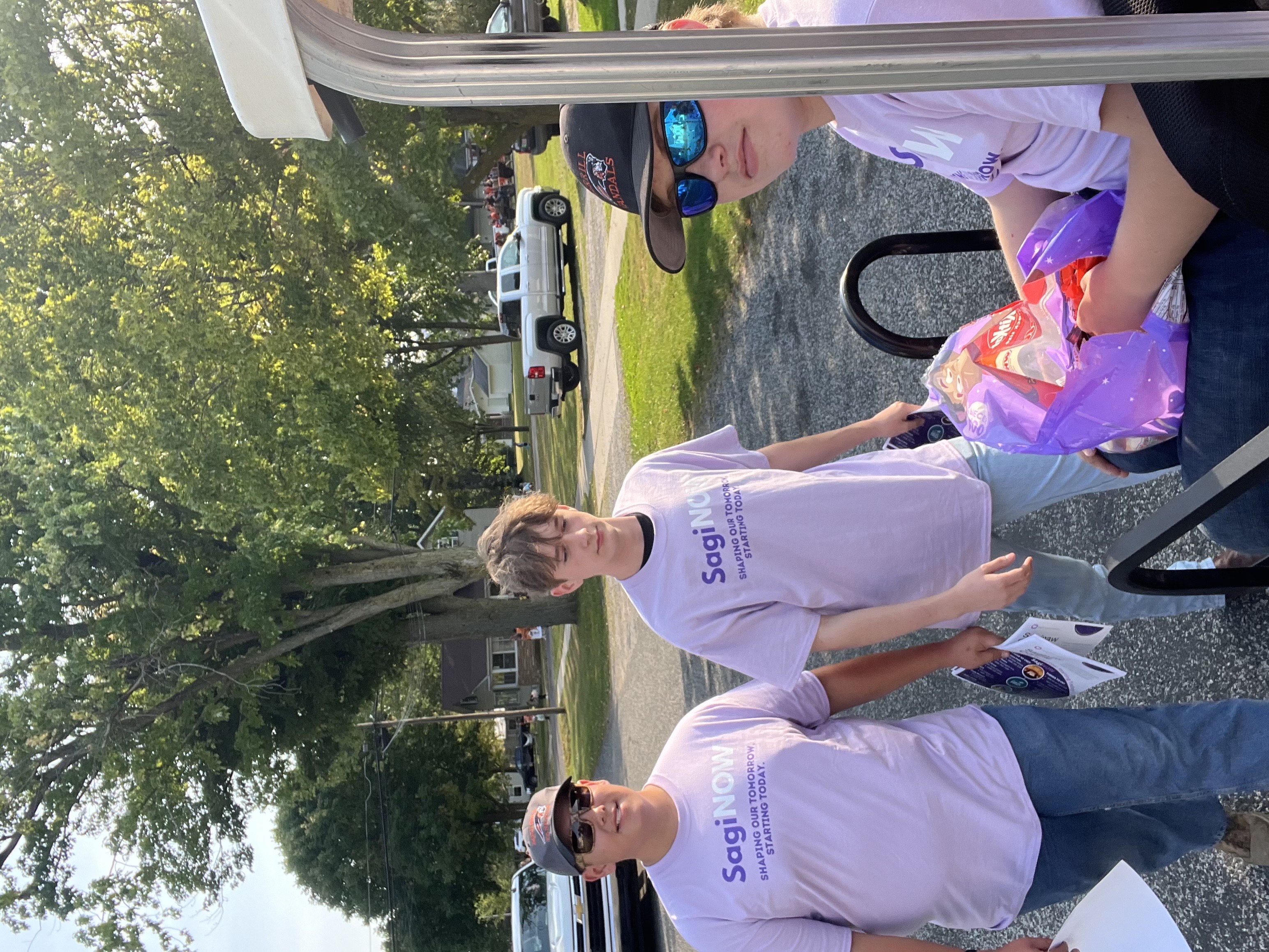 three student ambassadors wearing purple tshirts at a parade passing out candy in Merrill