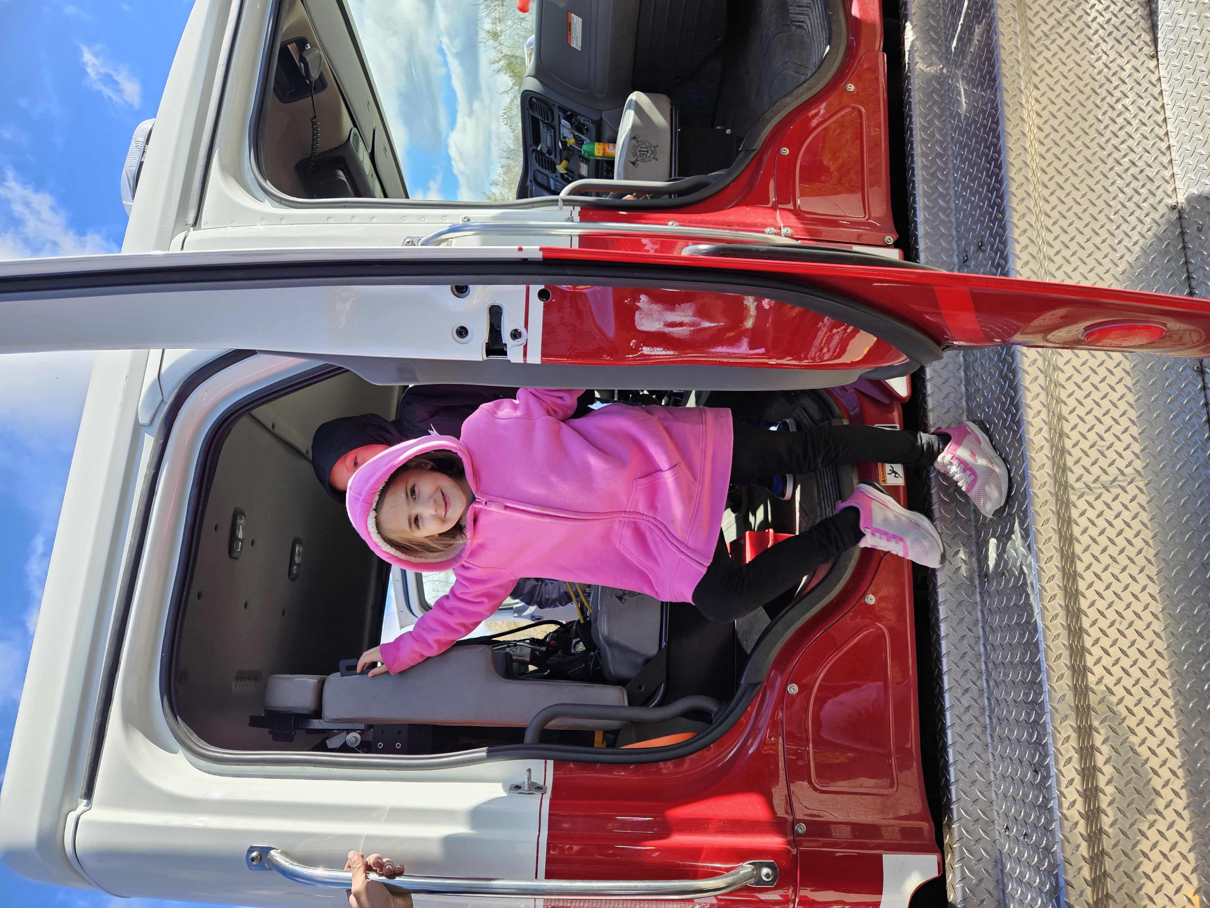 An MJT student in a pink fleece jacket stepping out of a fire truck