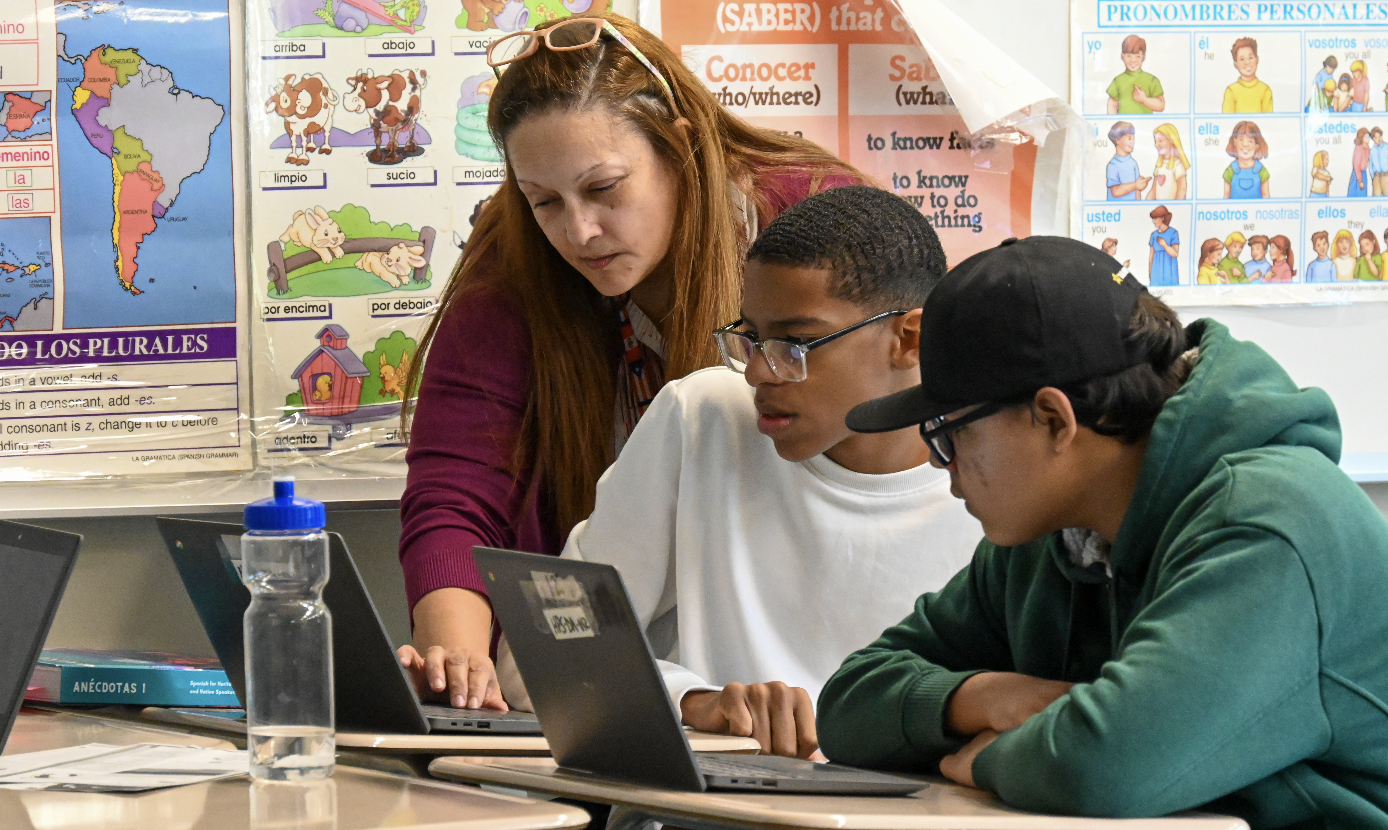 A teacher helps a student with work on their laptop