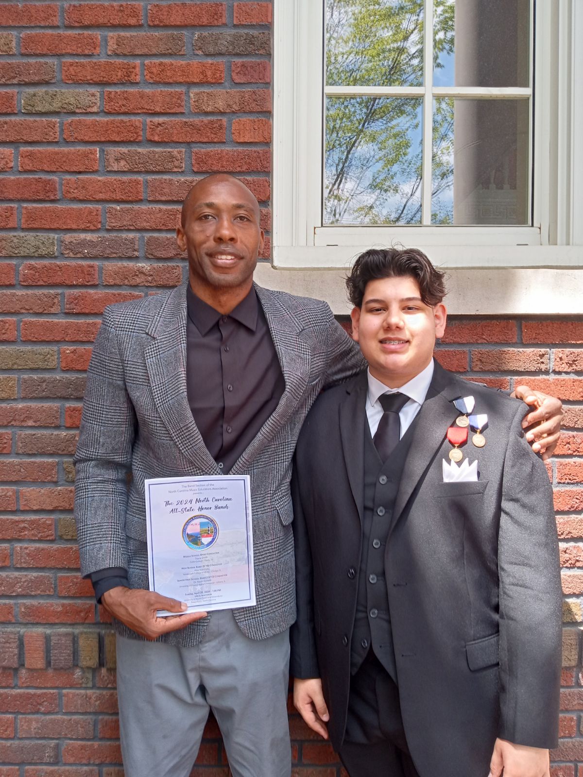 two men standing side by side holding an award