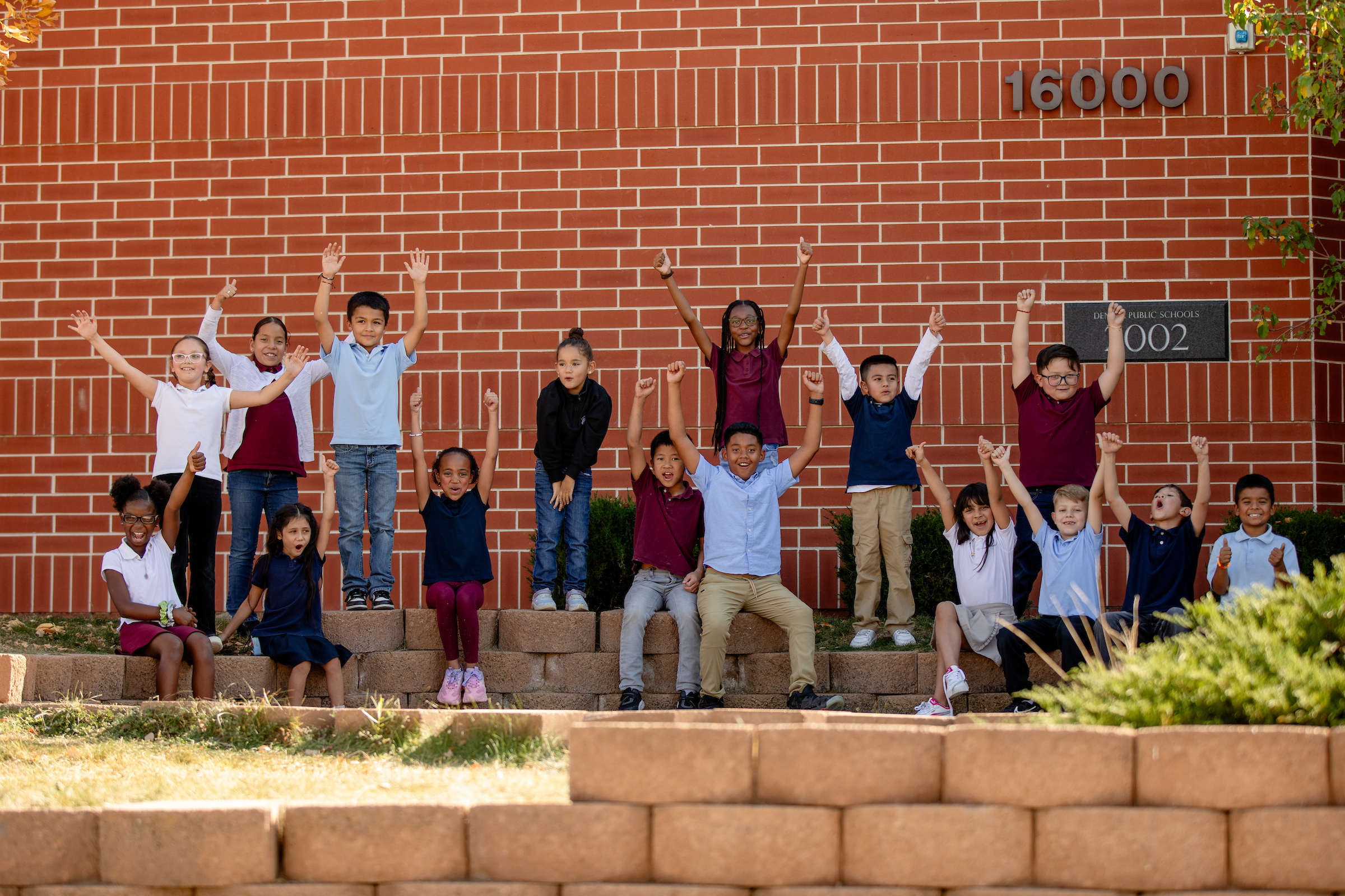 Lena Archuleta Students Pose in front of their school with their hands in the air, excited