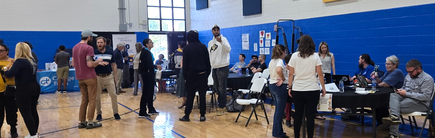 students milling around tables set up in the gym