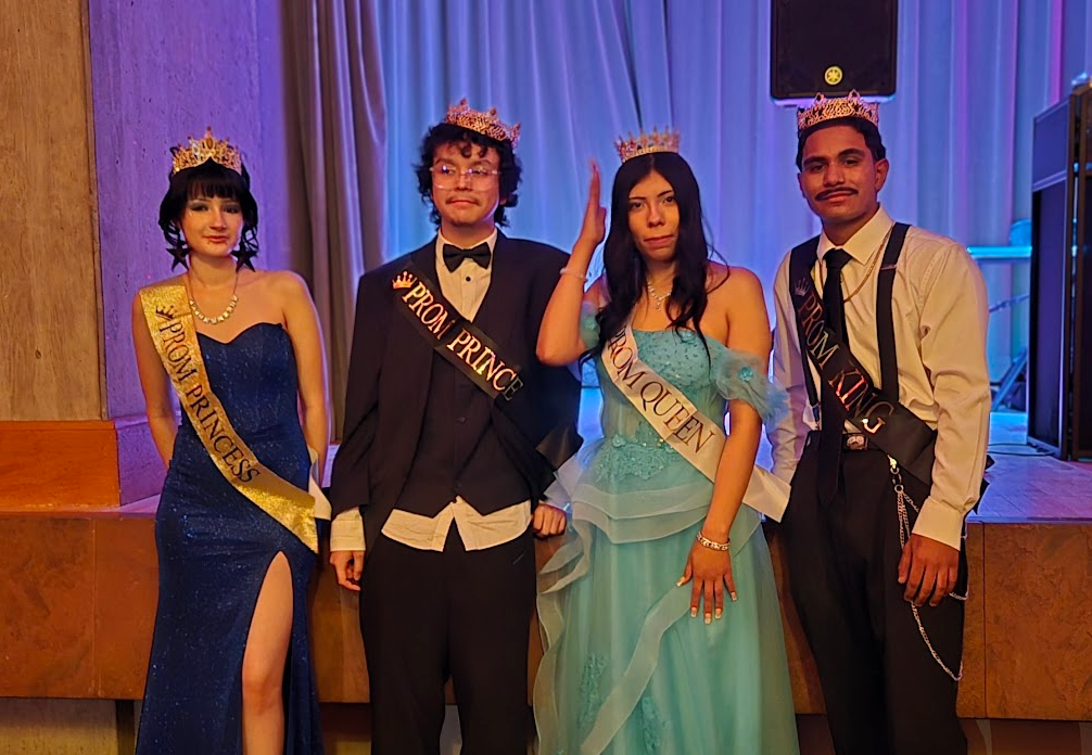 2 students in their prom outfits, wearing sashes that say "prom princess, prom prince, prom queen, prom king" and crowns
