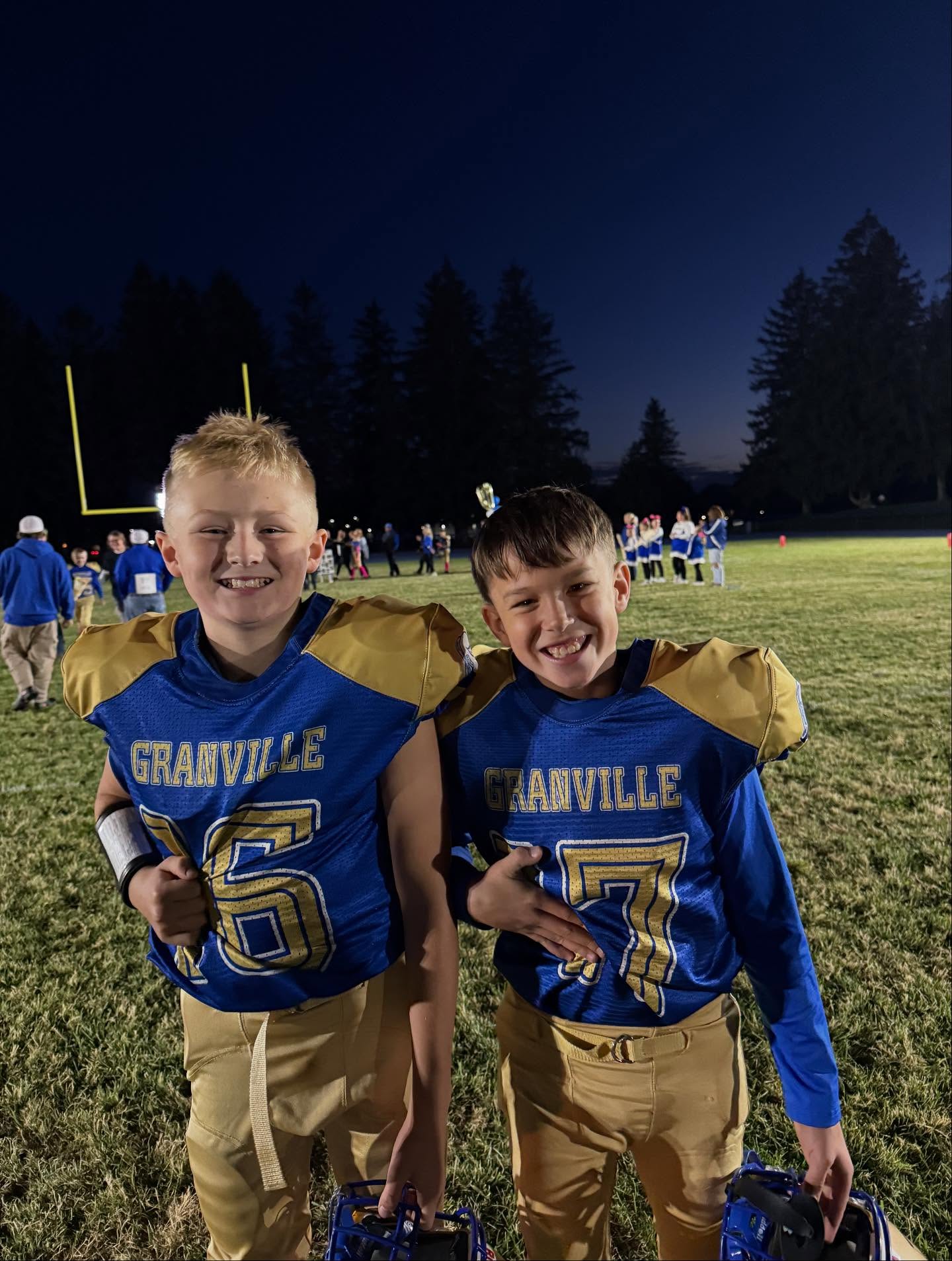 GES students in youth, blue and gold Granville, football gear creating a 6-7 sign out of their uniform by covering parts of their jersey numbers so only 6 and 7 show