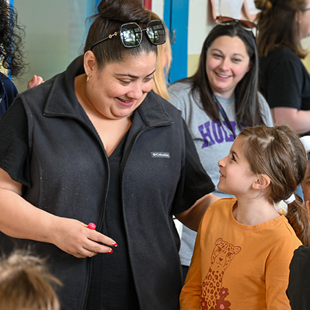 Adult with hand on student's shoulder, looking at student, as another adult looks on