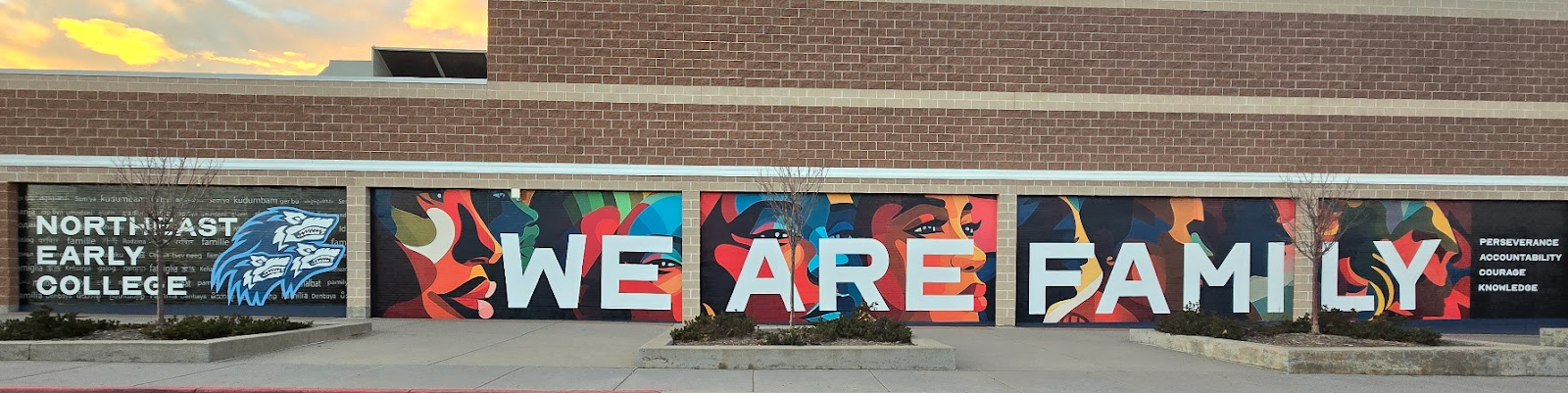 Exterior of Northeast Early College with a mural of colorful faces and "we are family" written over it. 