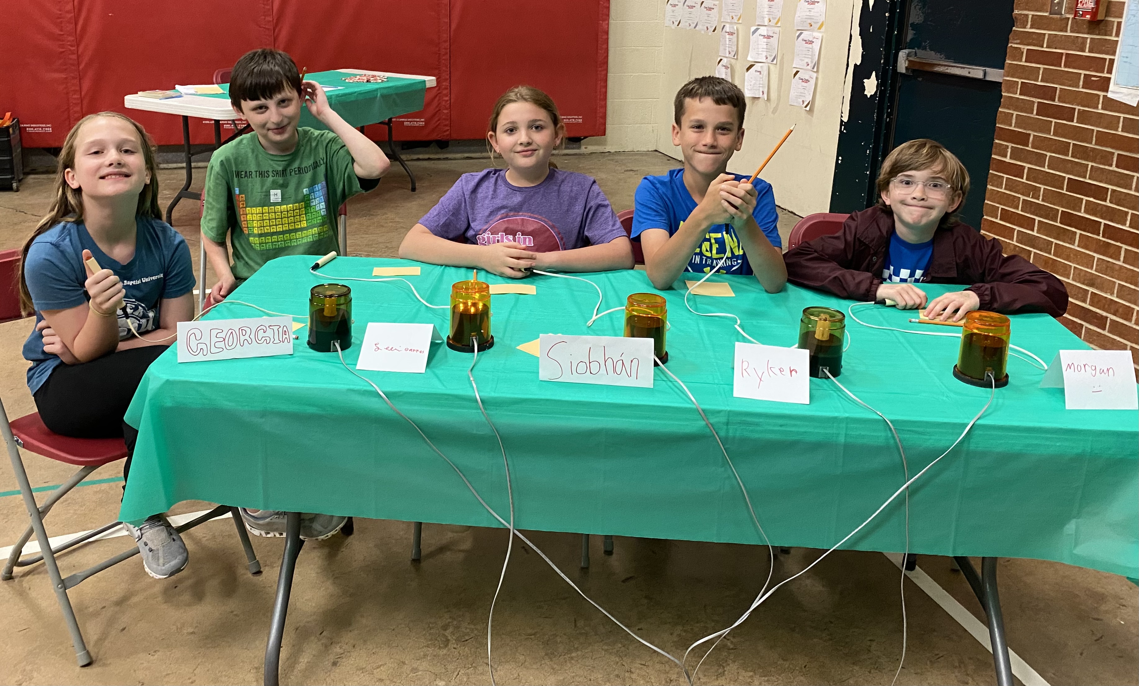 students smiling behind table