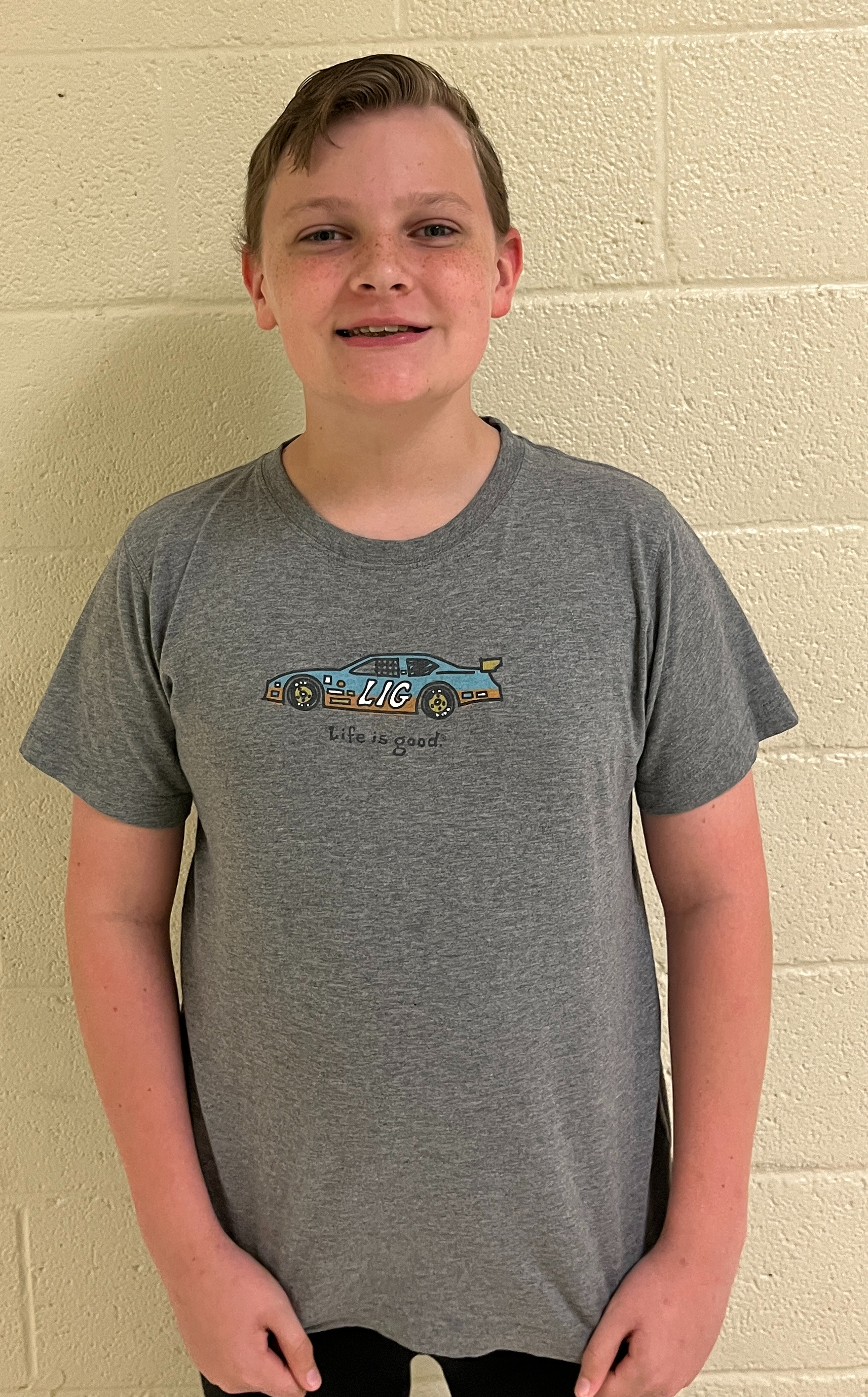 Student in a gray shirt smiling at the camera