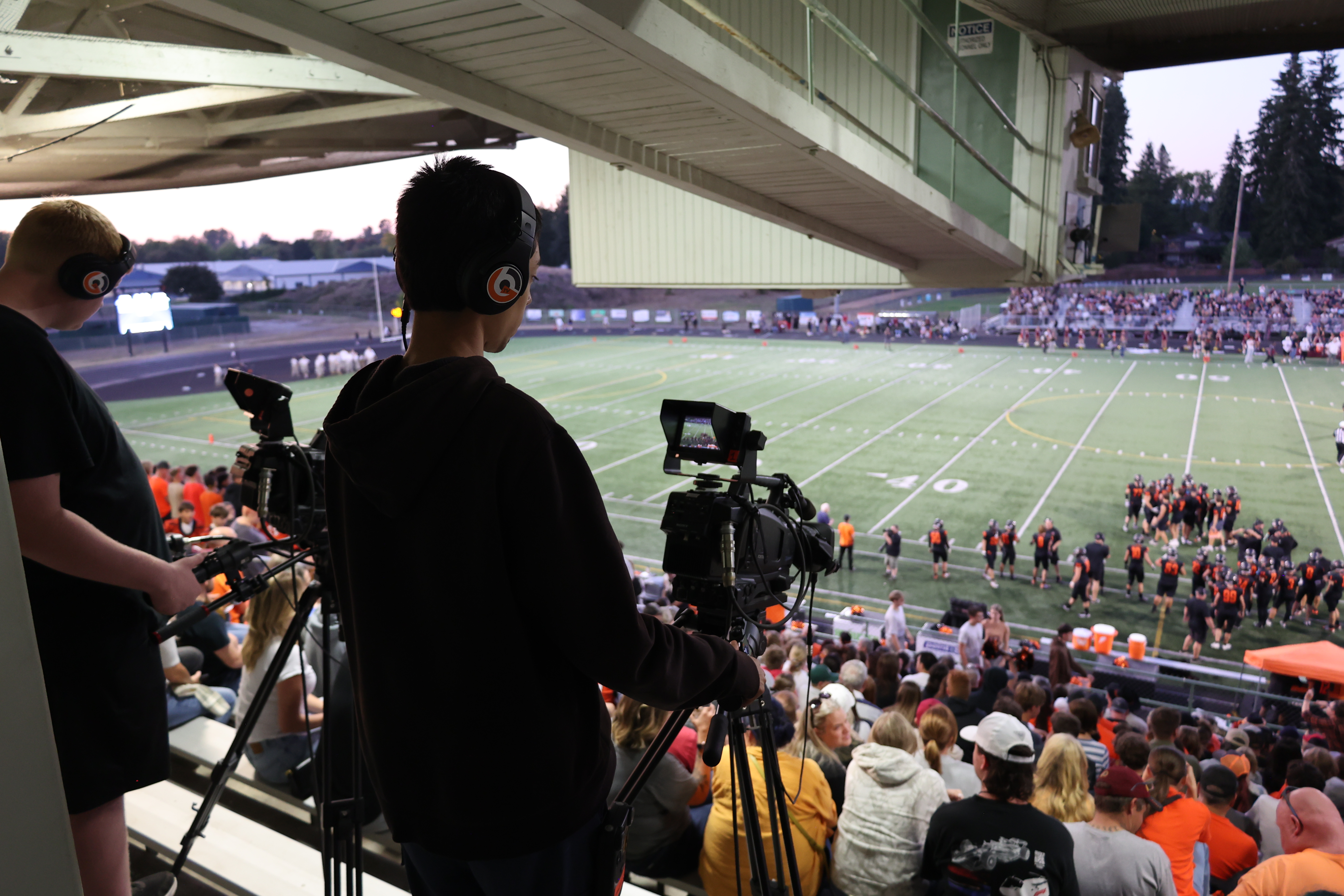 Two students film a football game