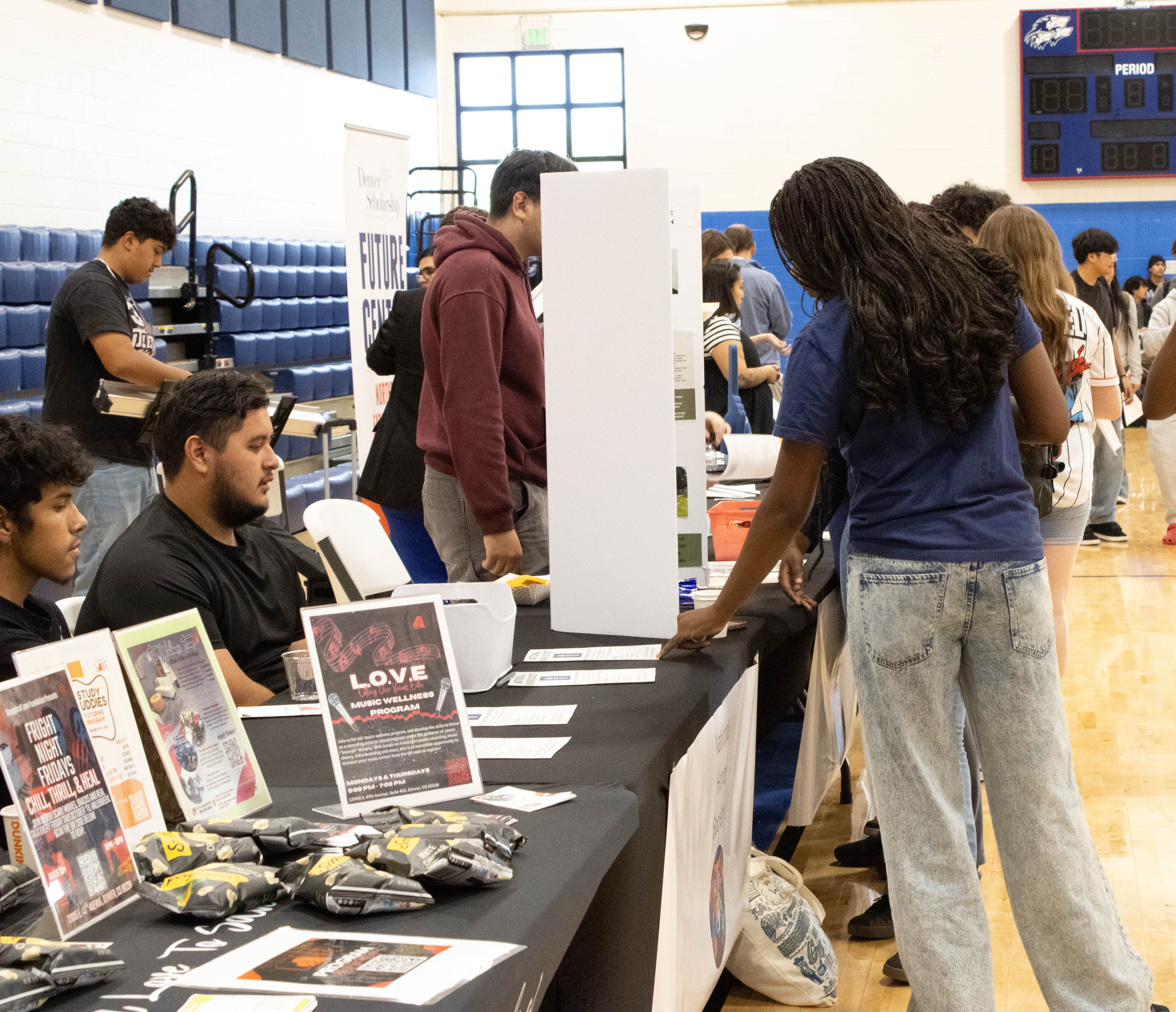 NEC student stands at a table at back to school night.