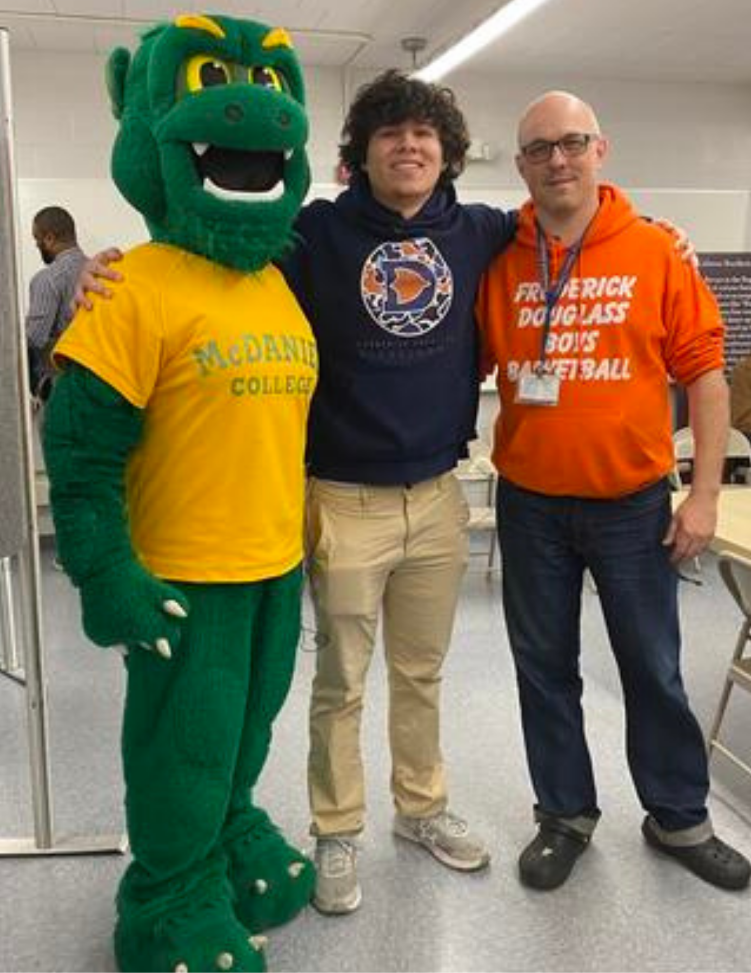 Malver Canales con la mascota del McDaniel College y un miembro del personal de Frederick Douglass