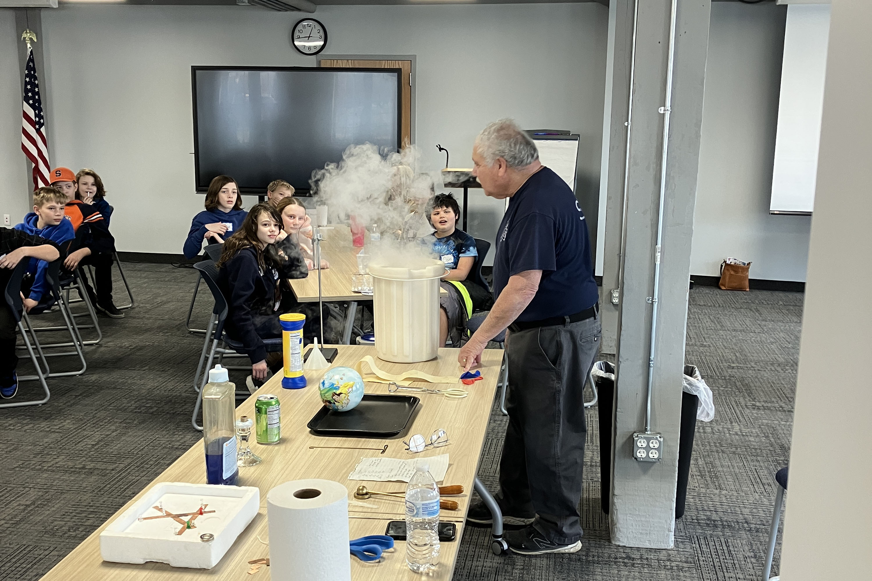 Students look on as presenter does science experiment with steam coming from bucket
