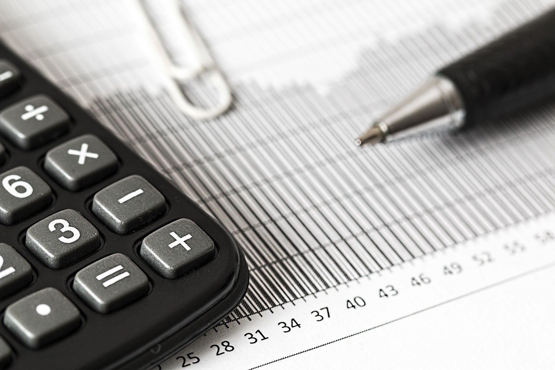 calculator on paper lined with numbers and a pen