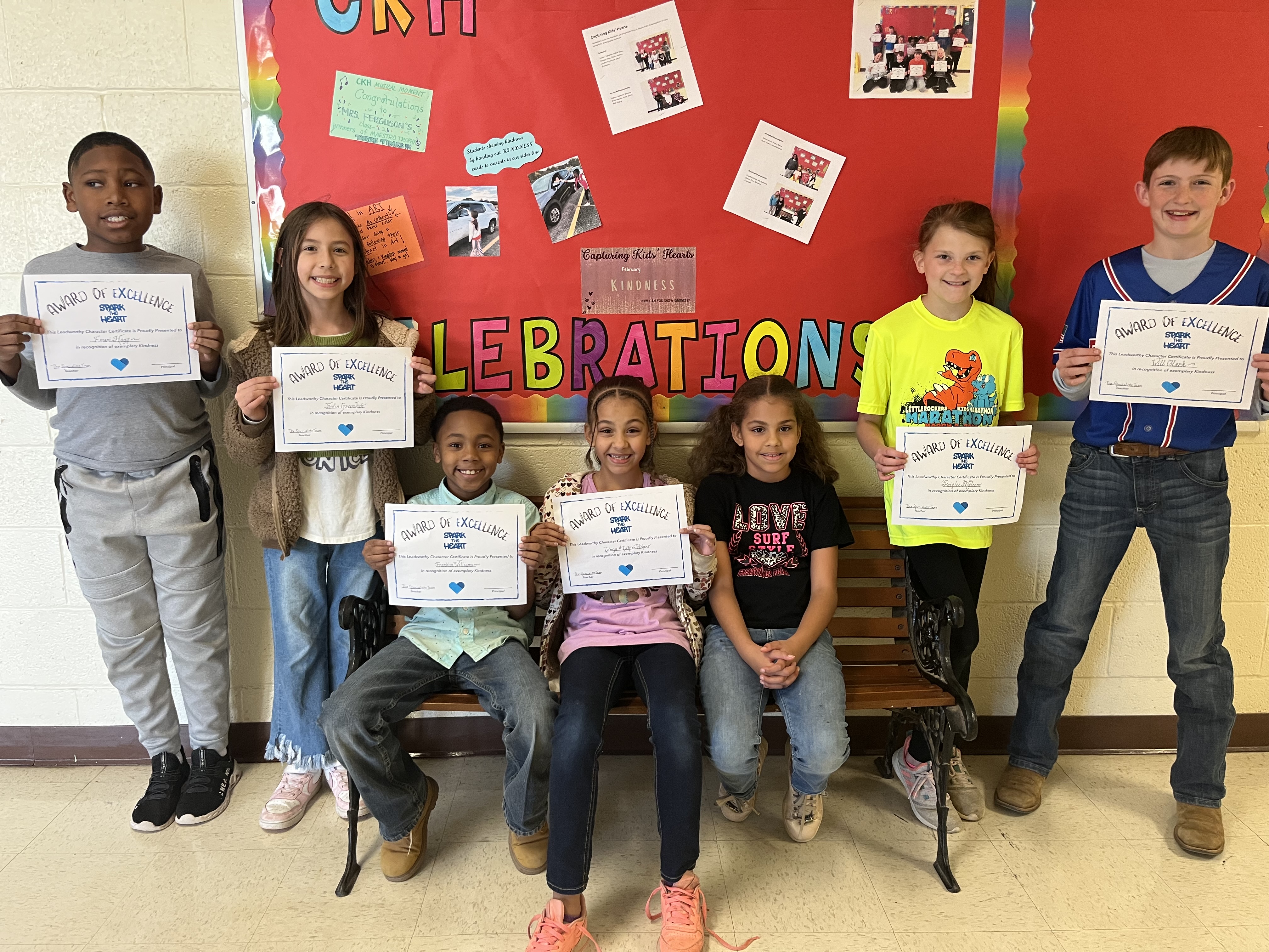 Kindness winners smiling at the camera holding their certificates