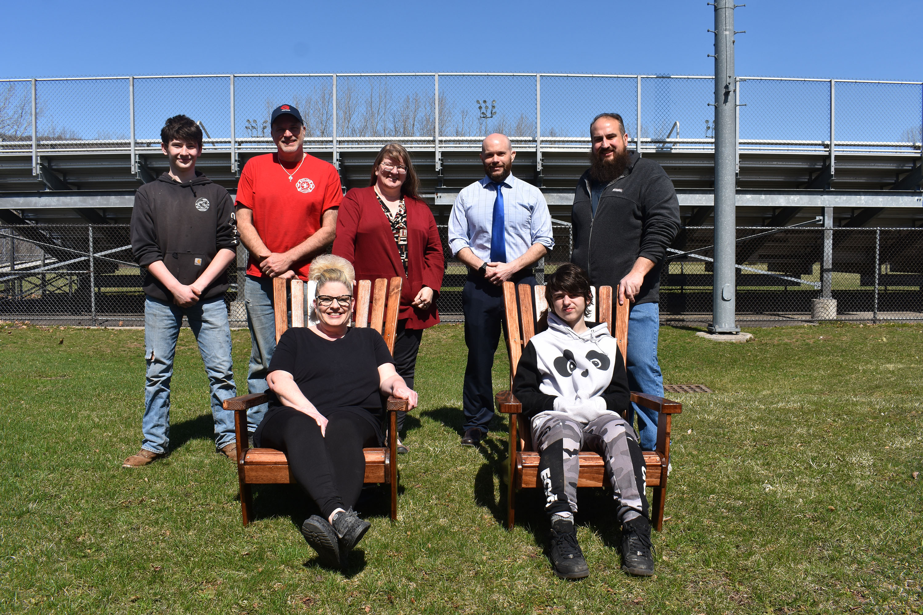 Seven people outside with two Adirondack chairs