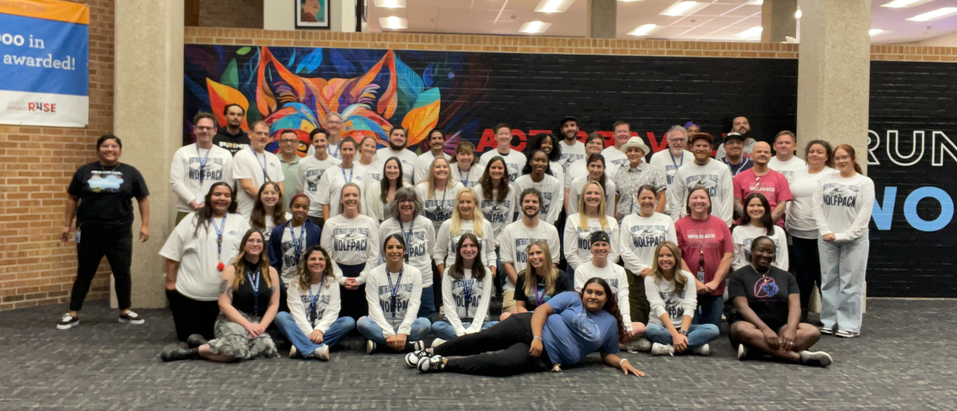 NEC staff posing in front of the Wolf mural