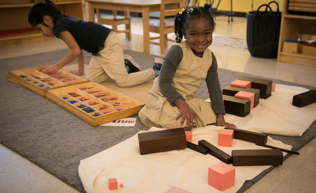 Smiling student with Montessori pink tower