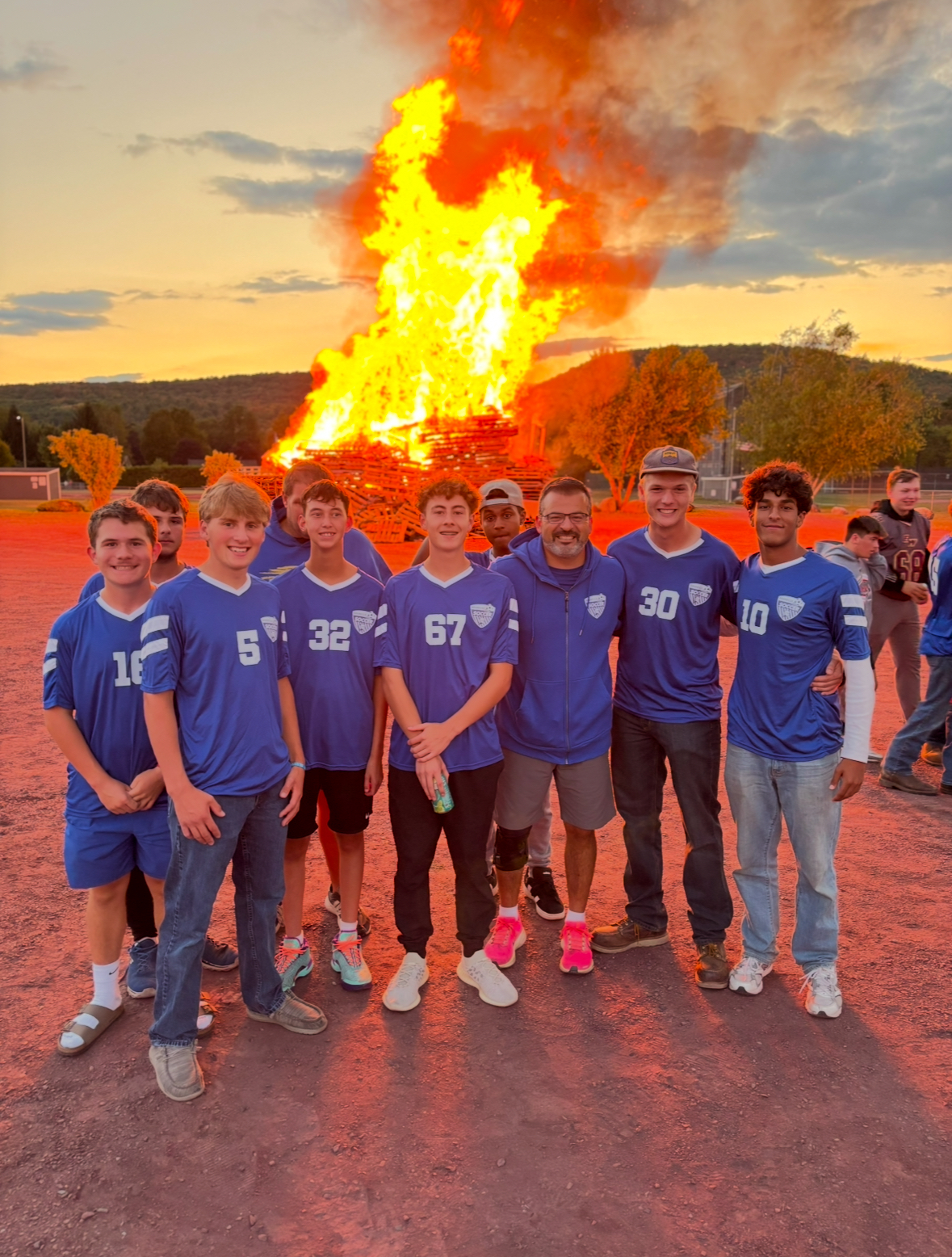 varisty soccer with bonfire behind team
