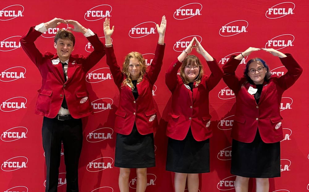 FCCLA students do an "OH-IO" pose in front of a banner