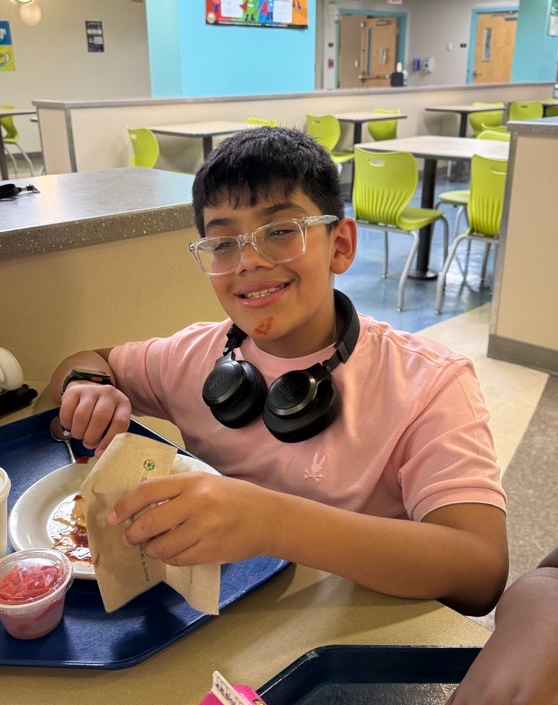 Jayden smile at the camera while eating dinner.