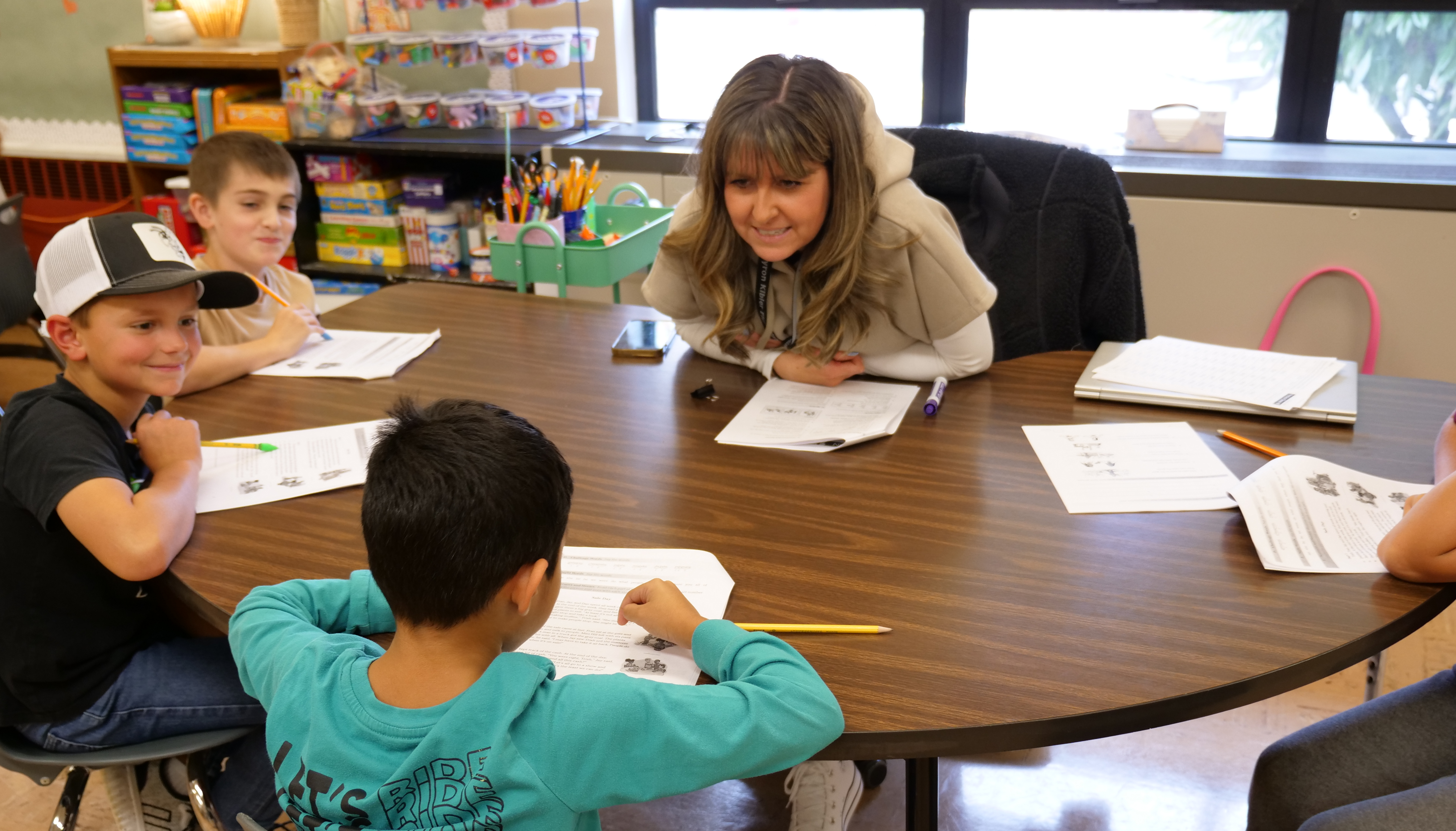Students sitting around a small group table engaging in WIN time,  working on reading skills