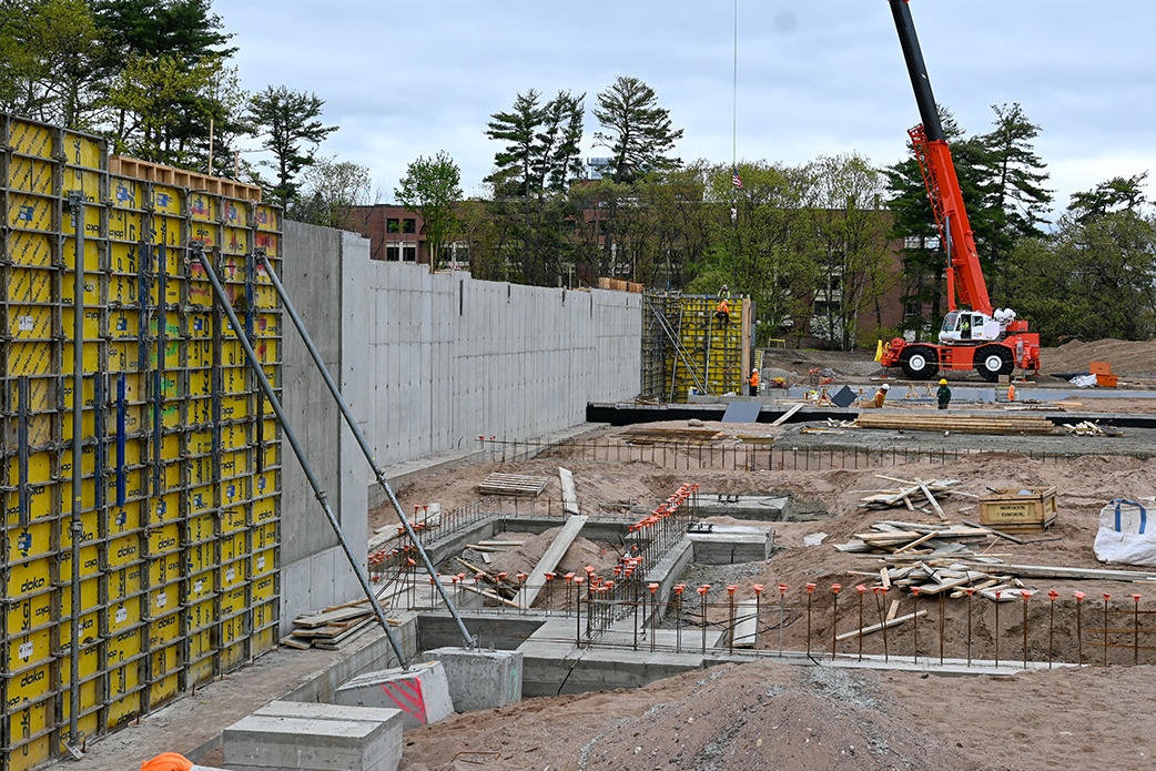 Construction workers and crane by retaining wall