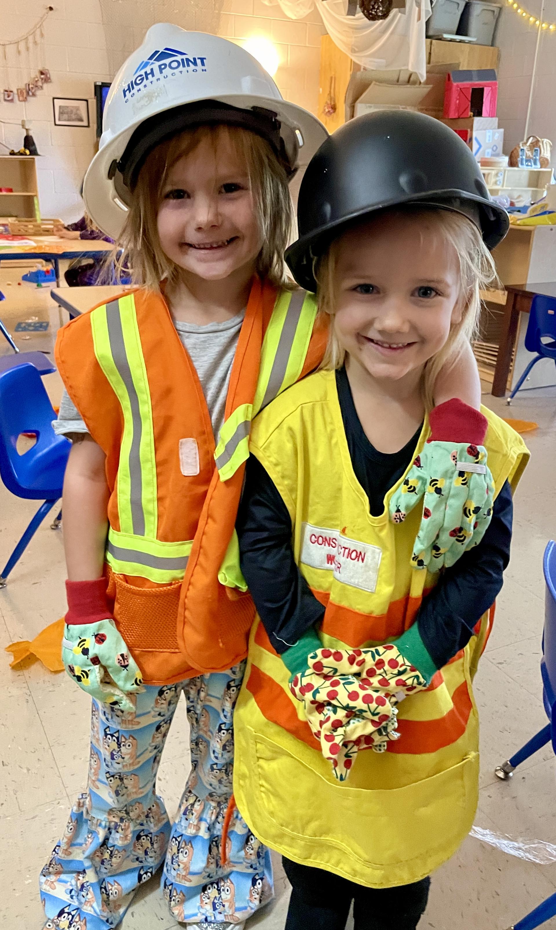 two girls with hard hats and construction vests