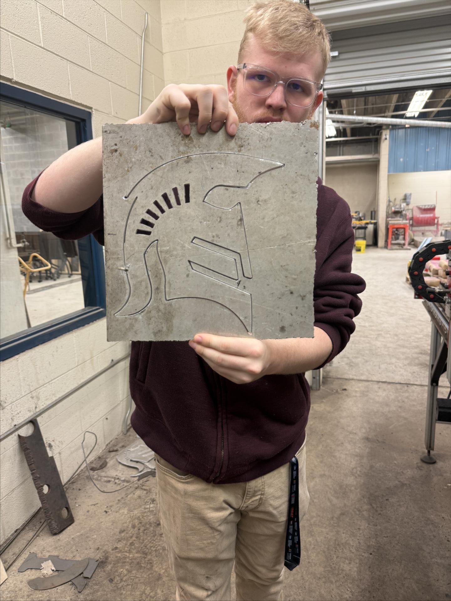 A student holds up a fabricated metal design of Eastside High School logo