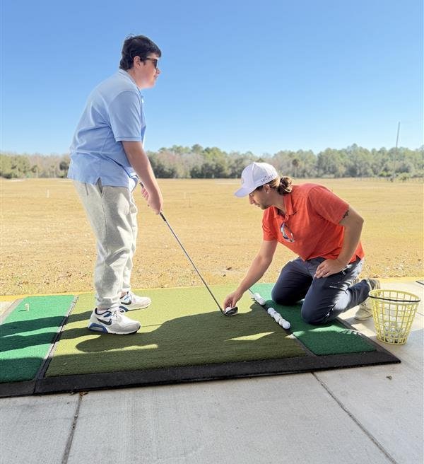 Nick learning how to hold the club and stance and where to aim for contact with the ball