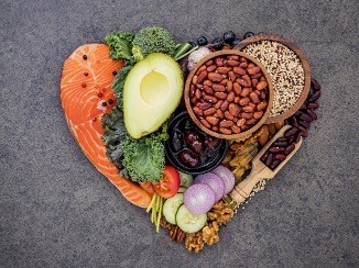 Heart shape made with healthy food such as salmon, avocado, nuts, and cucumbers