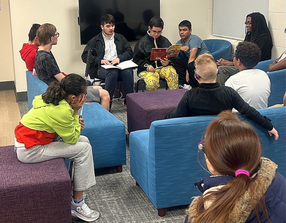 Juniors reading to the students all sitting on couches