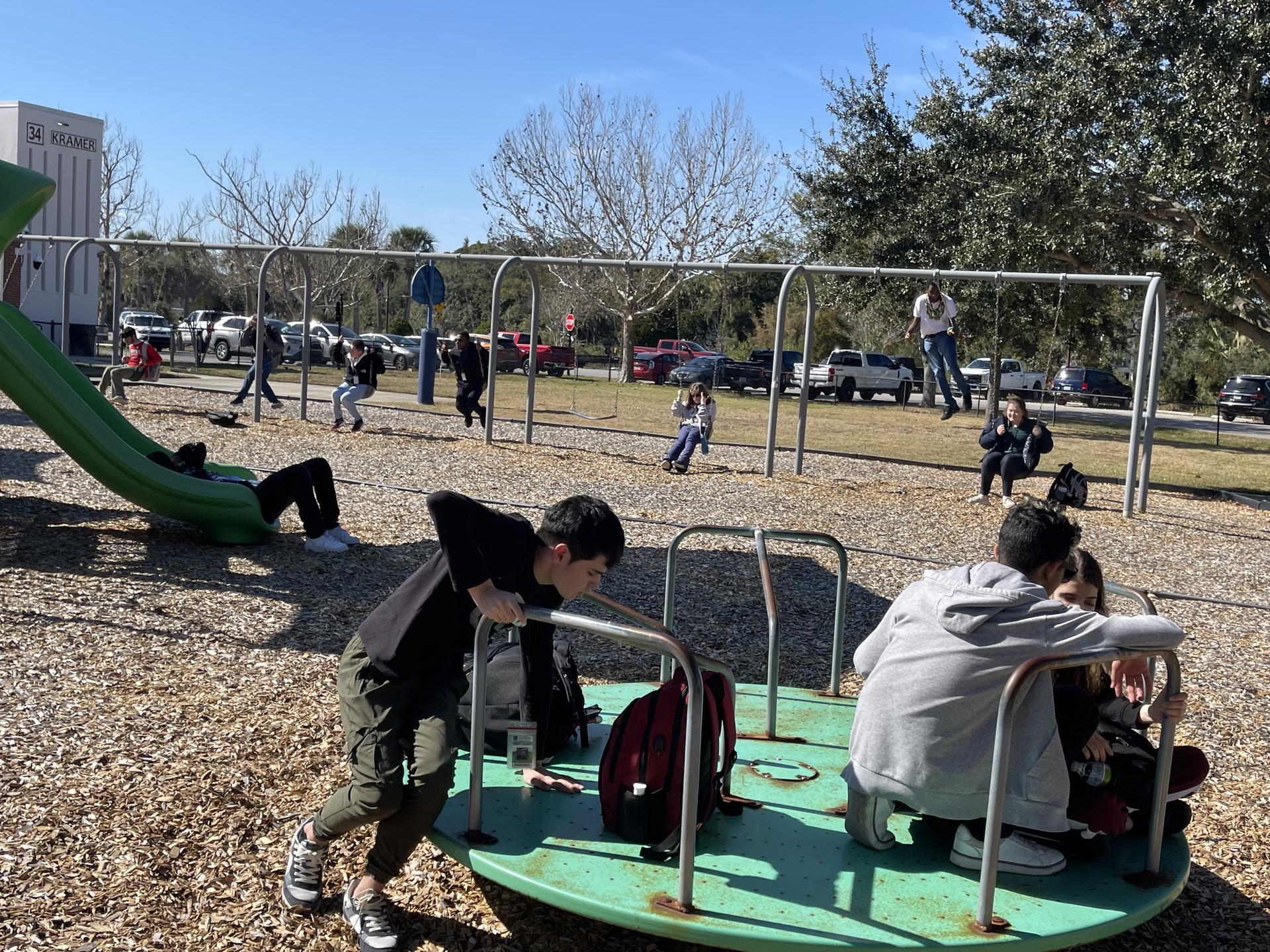 students fill the swings, slide, and merry-go-round