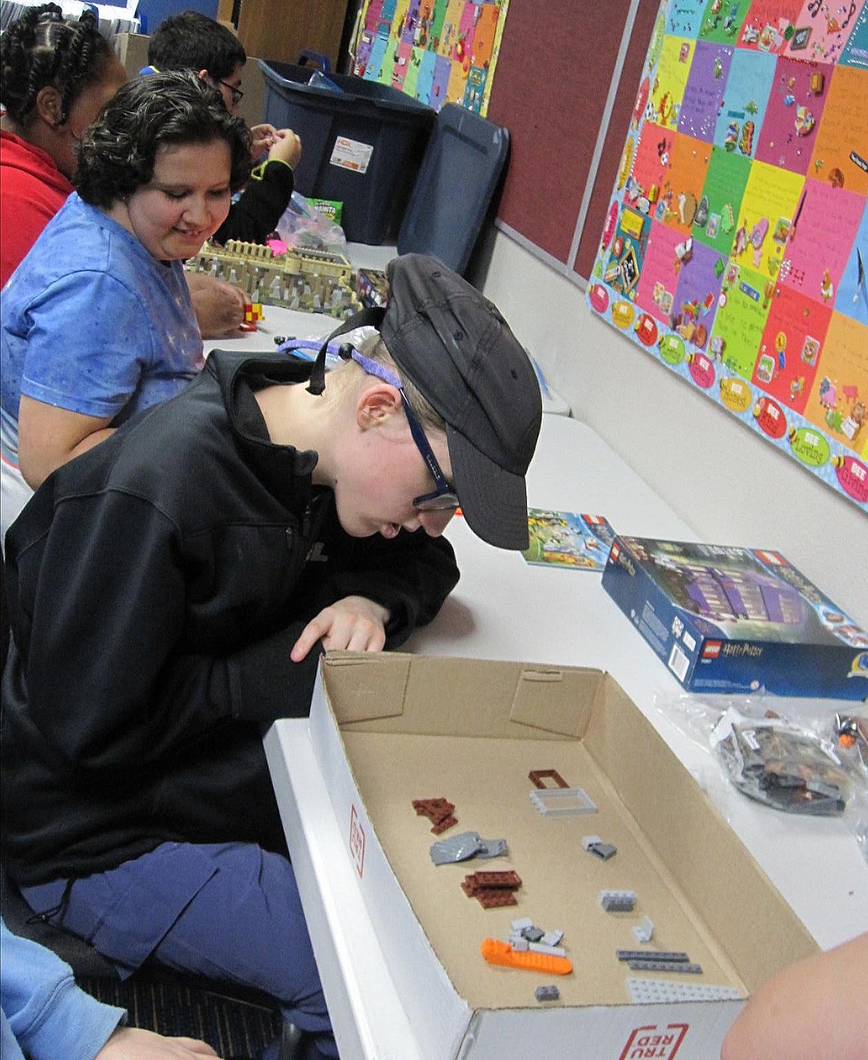Maddie scans Lego pieces separated in a box while Janna looks on