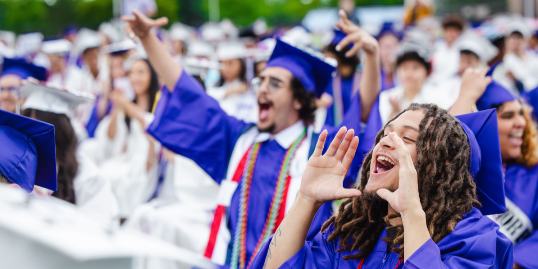Graduates cheering while wearing caps and gowns