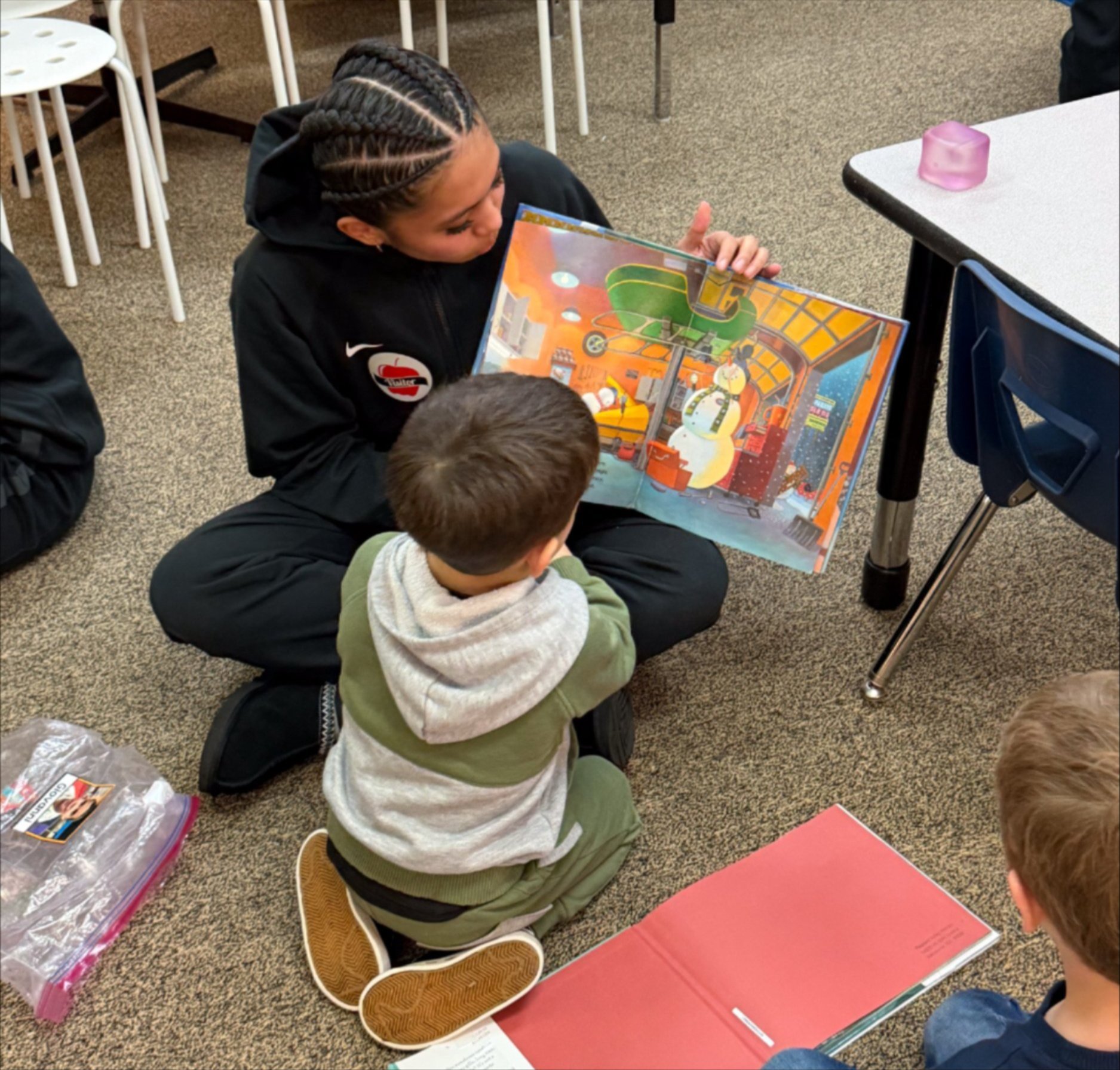 A high schooler reads to two primary school students