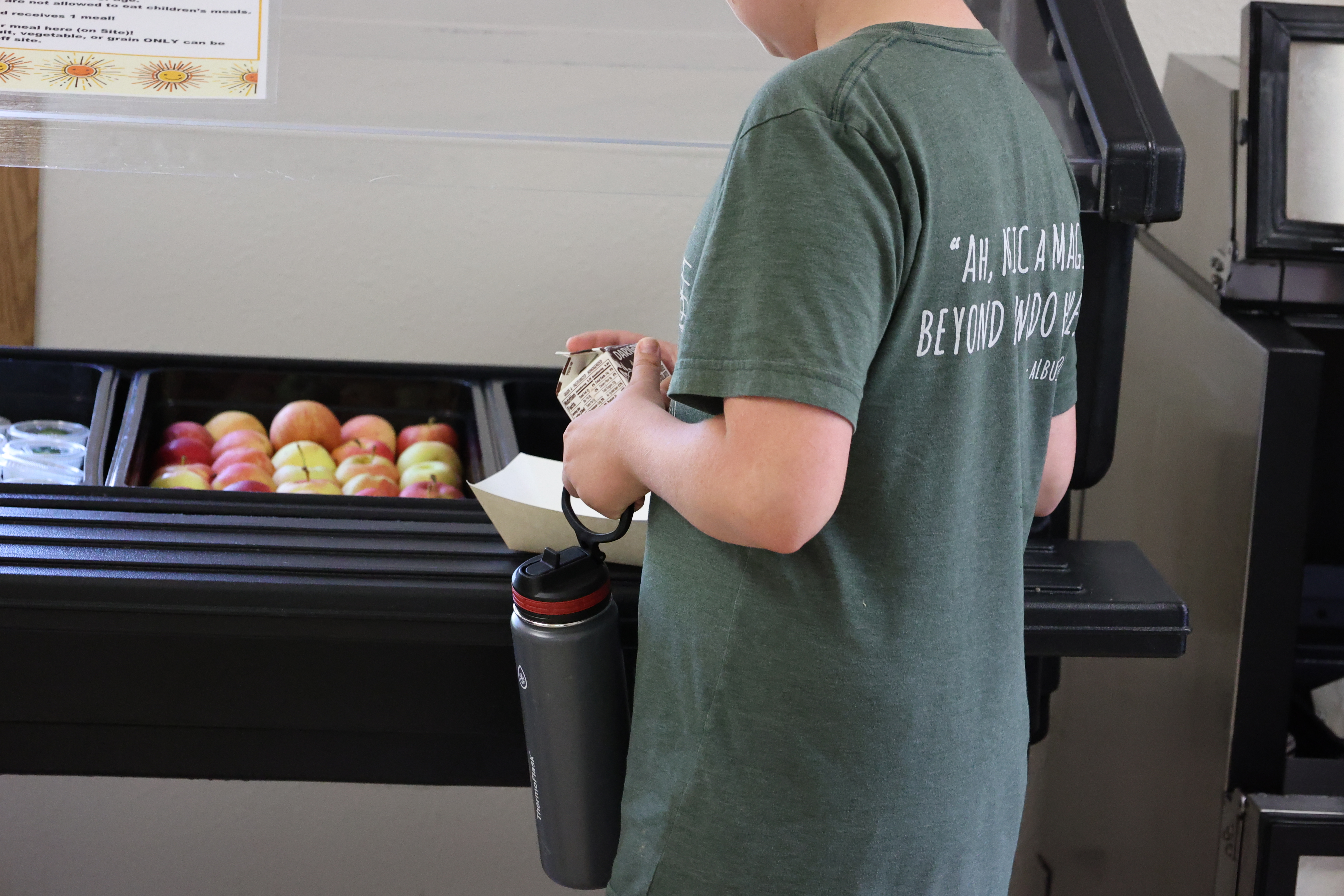 A student holds a milk carton and evaluates summer meal options