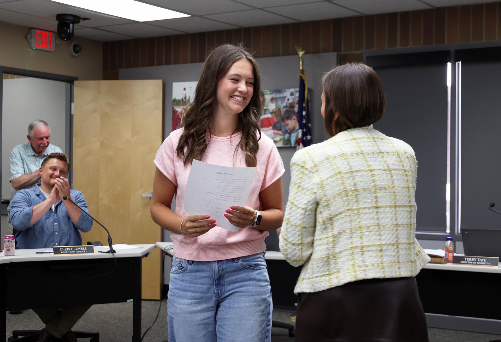 Addison Juhnke smiles after taking the oath of office as board directors look on and applaud