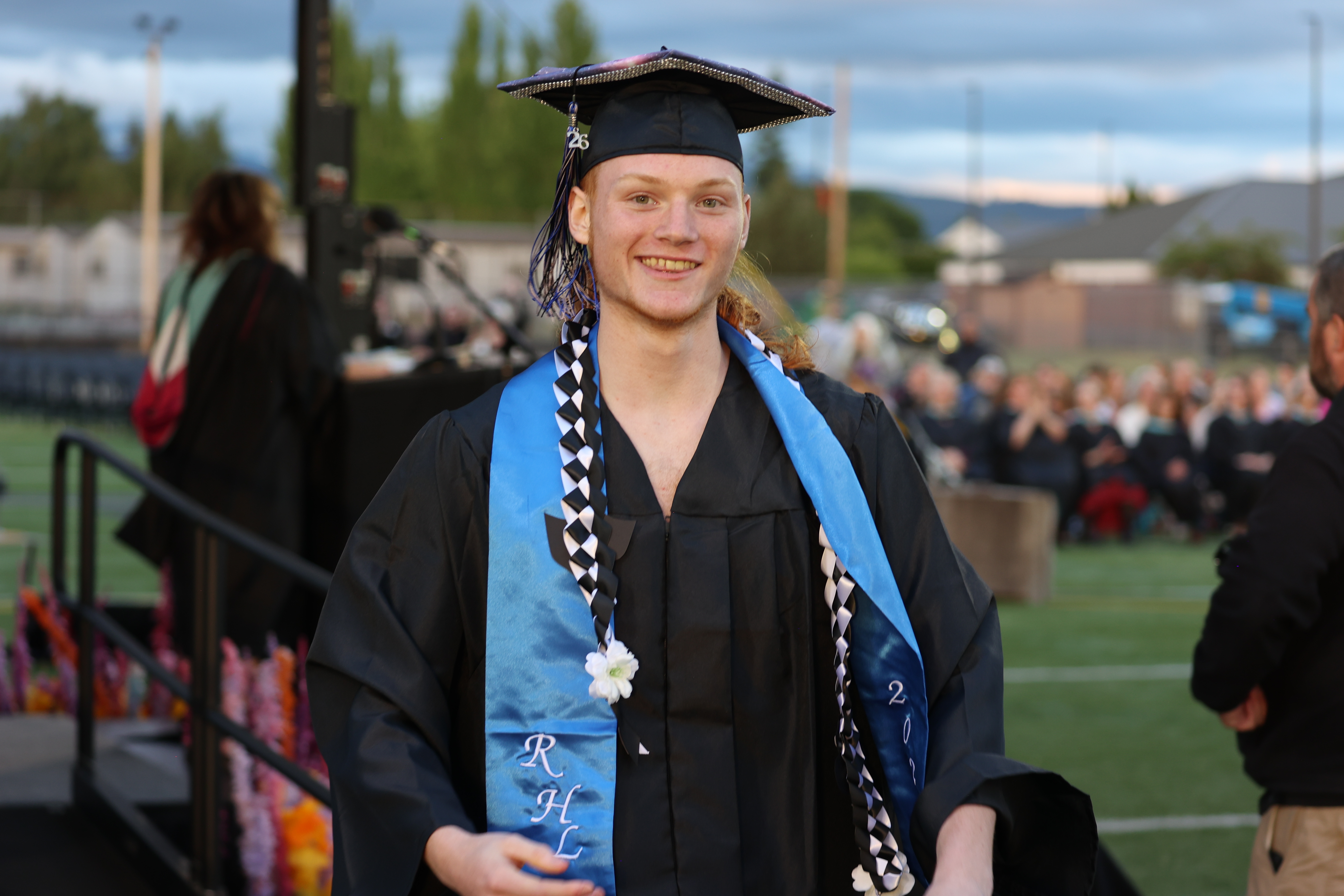 A graduate smiles at the camera after receiving a diploma