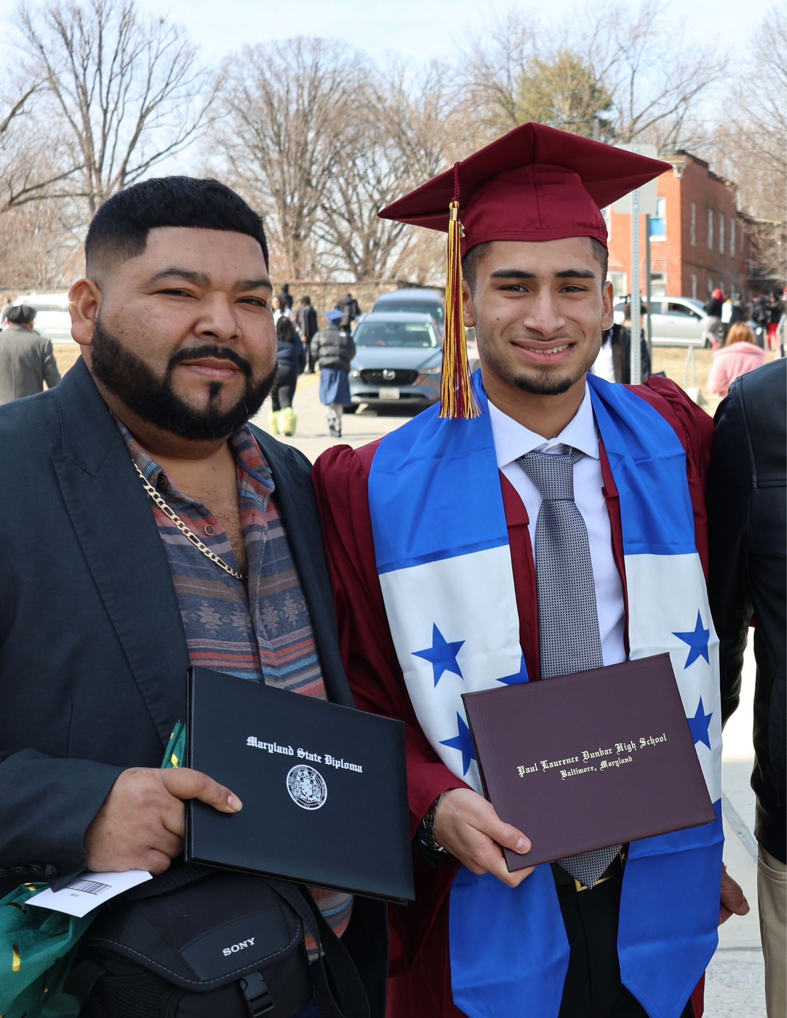 Padre e hijo recién graduado en la ceremonia de graduación de la promoción de 2025.