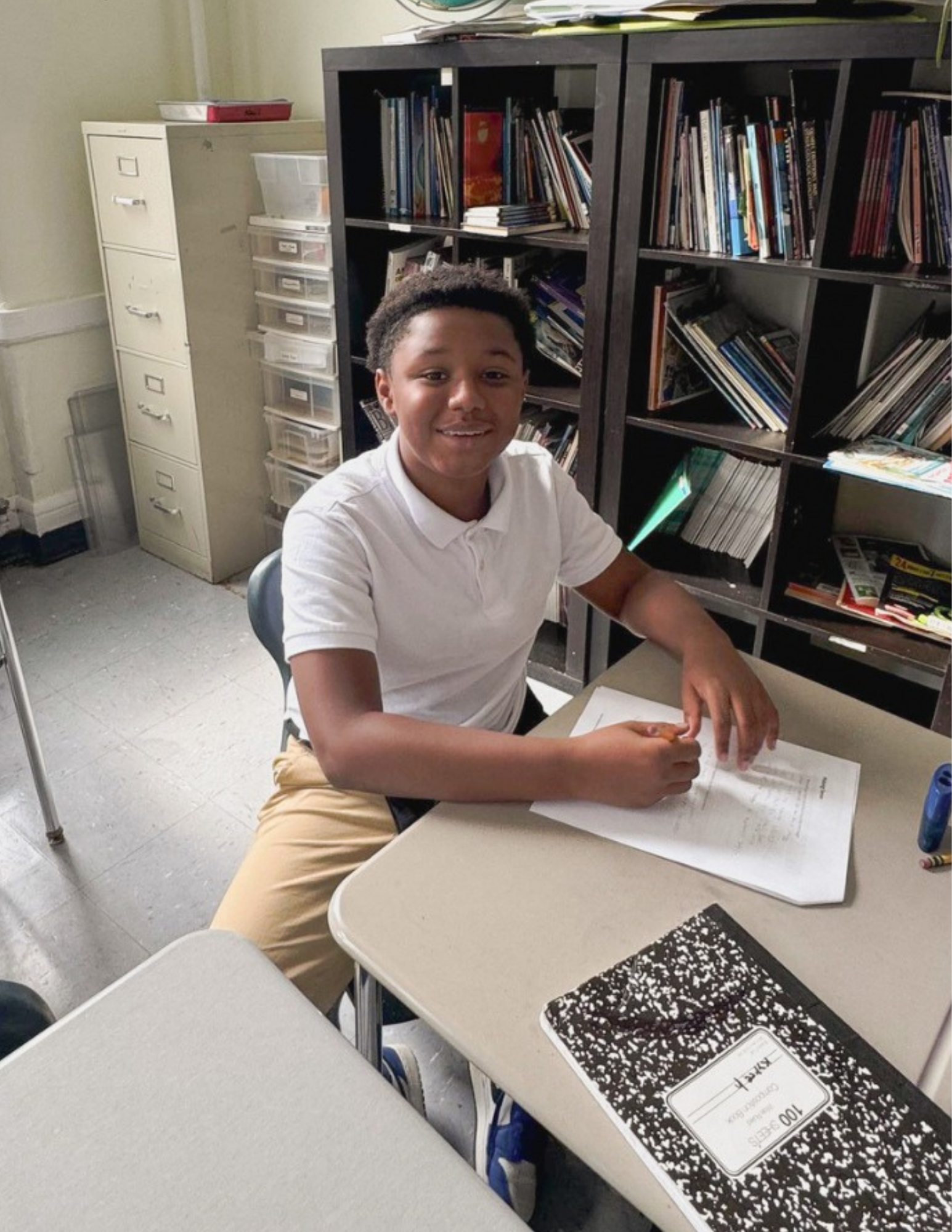 un estudiante sentado en su pupitre escribe en una hoja de papel