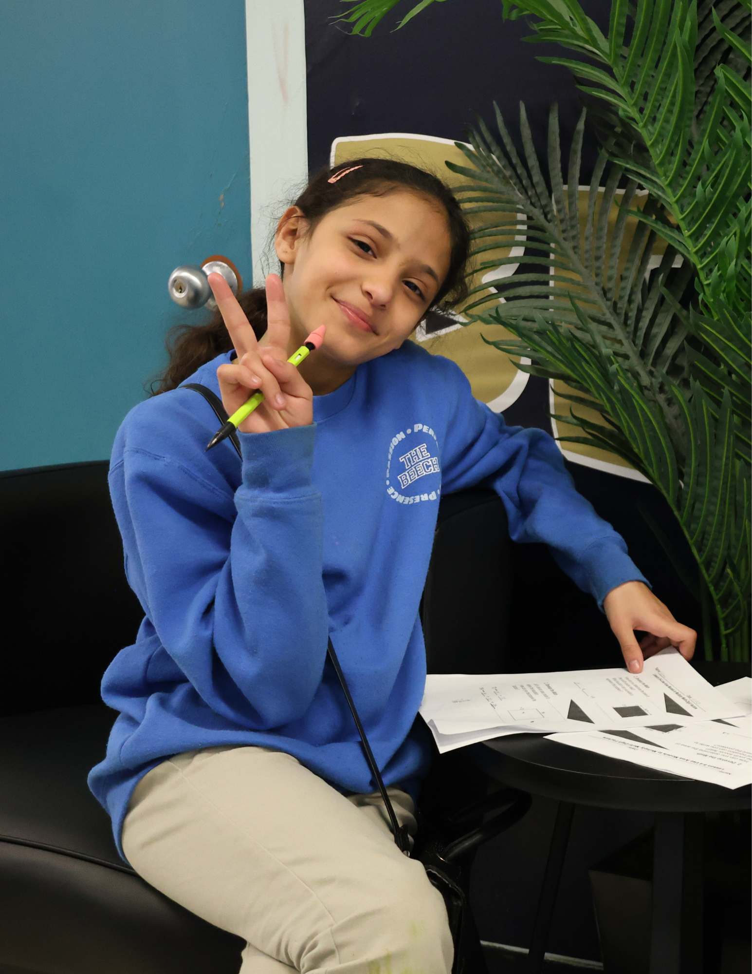 Una estudiante sonríe sosteniendo un lápiz y formularios