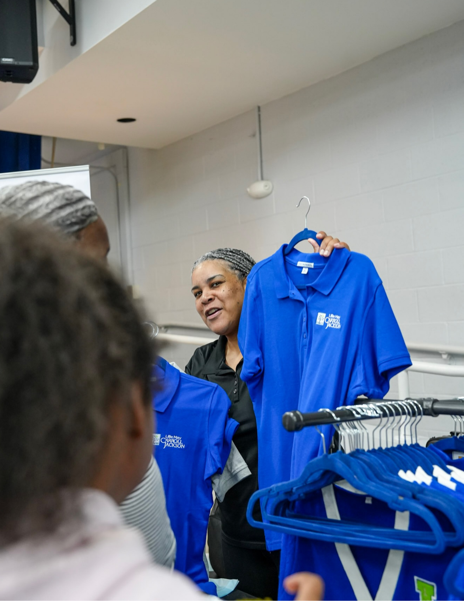 Staff member hands out uniform shirts at Lillie May Carroll Jackson School