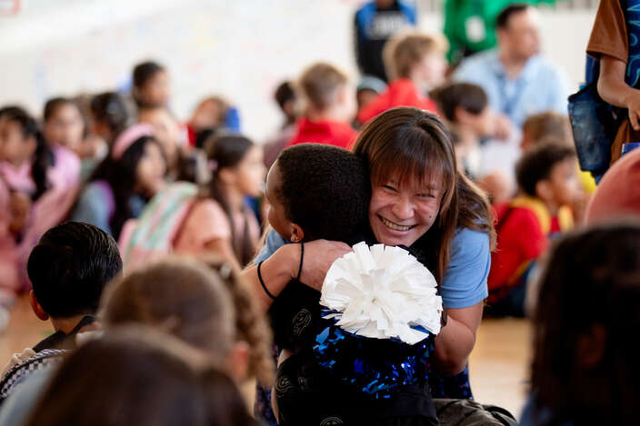 A teacher hugs a student at a pep rally