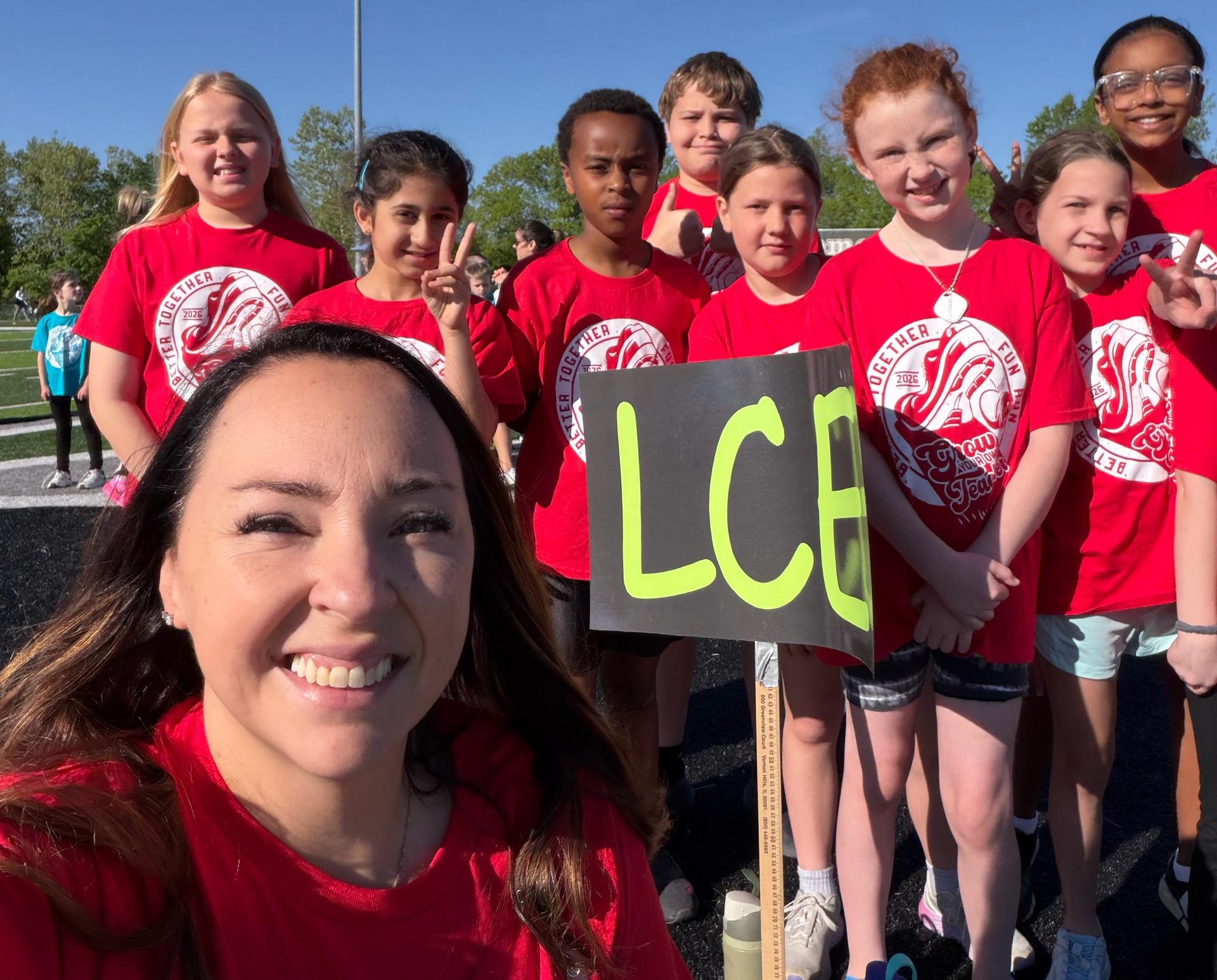 A variety of boys and girls in red t-shirts, some holding a black and yellow sign reading 