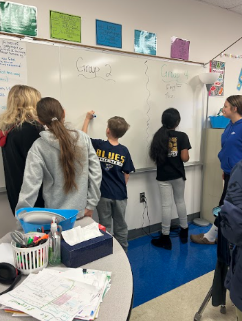 Students team up at the board, working in Vertical spaces during a CKLA lesson
