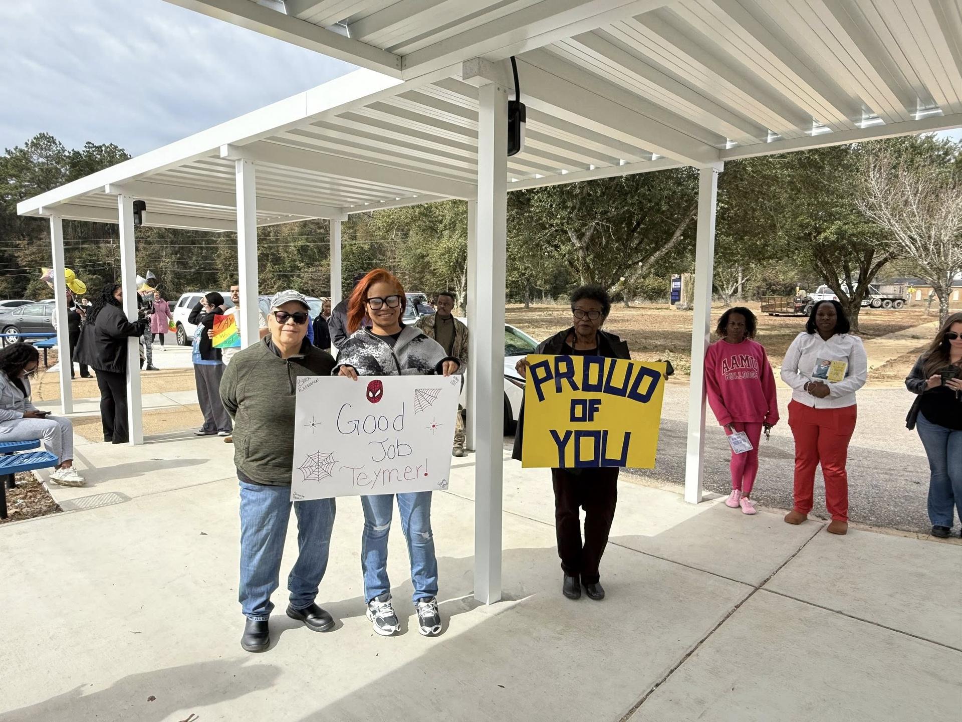 Picture of Teacher of the Year Recipient Ms. Venetia Smith, holding flowers and placard. 