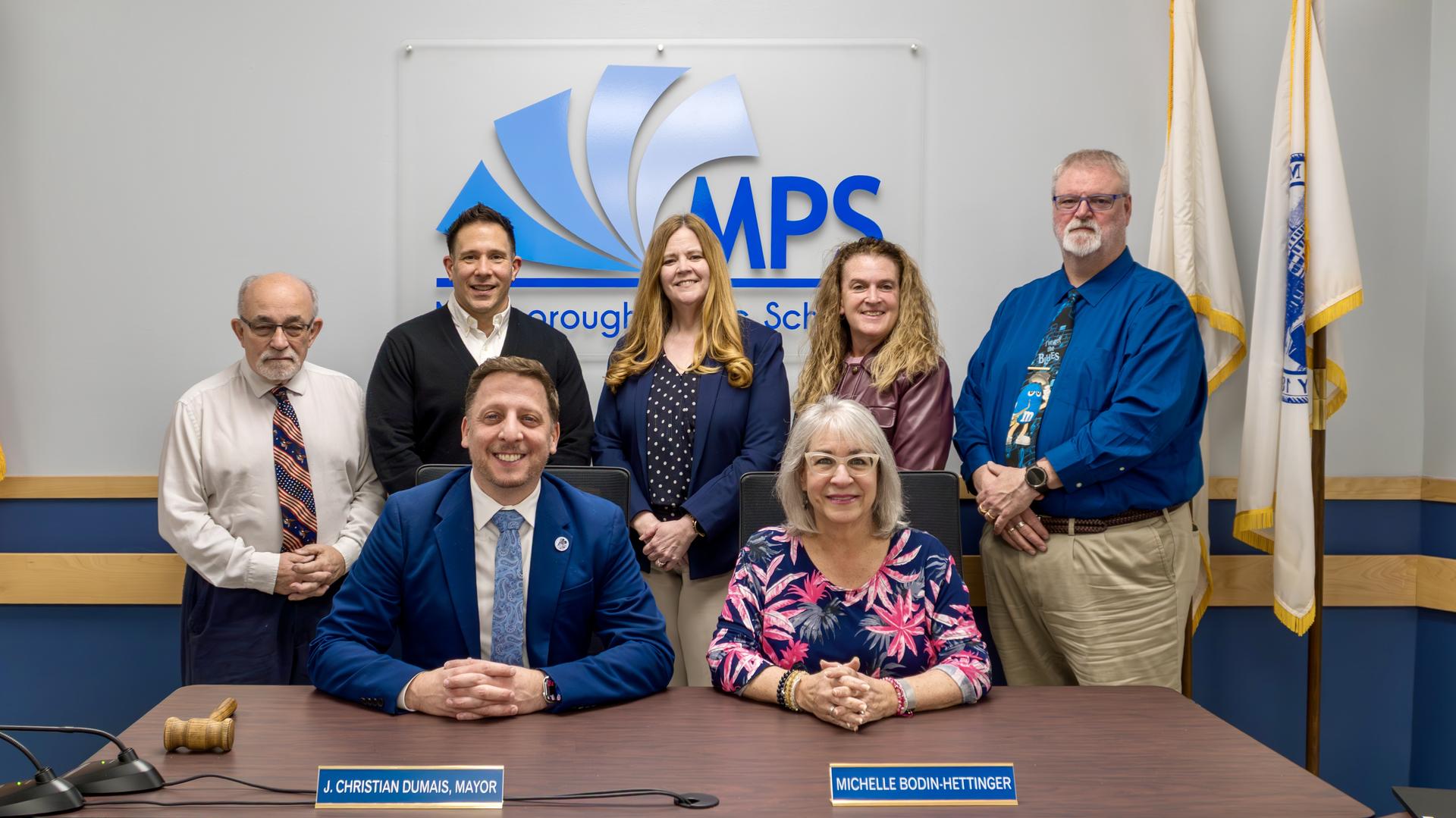 Marlborough School Committee group photo in front of a wall with the MPS logo.