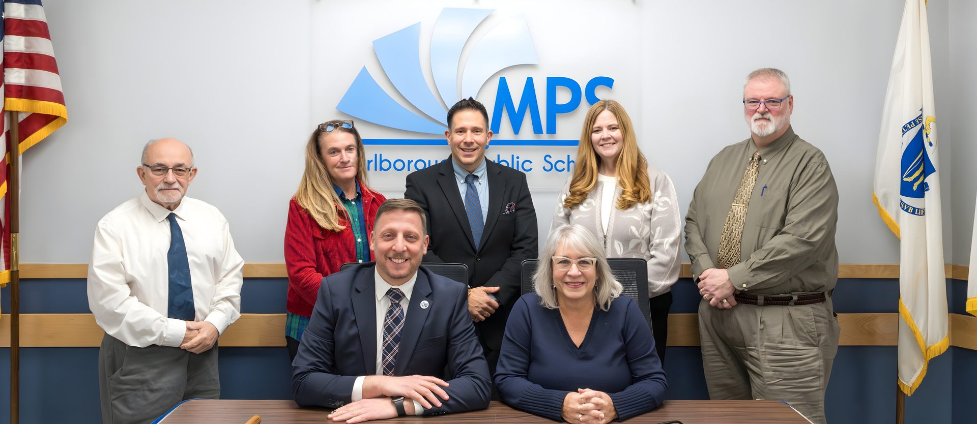 Marlborough School Committee group photo in front of a wall with the MPS logo.