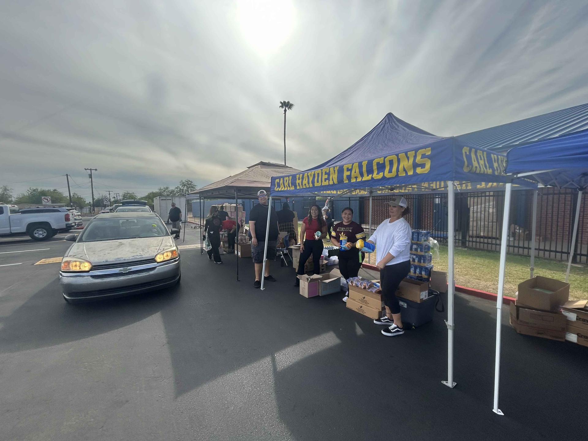 Parking lot with a car, people, boxes, and a tent labeled 