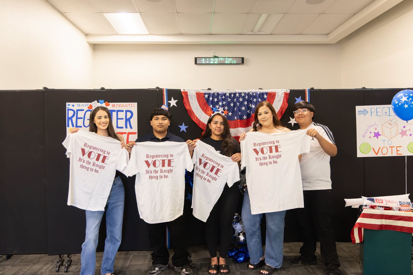Five individuals hold white T-shirts reading 